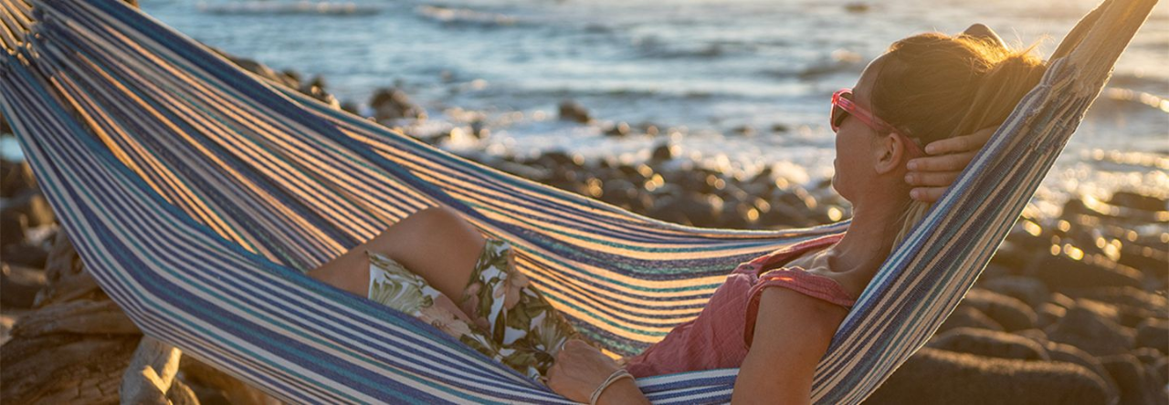 Frau chillt an der Küste in einer Hängematte.